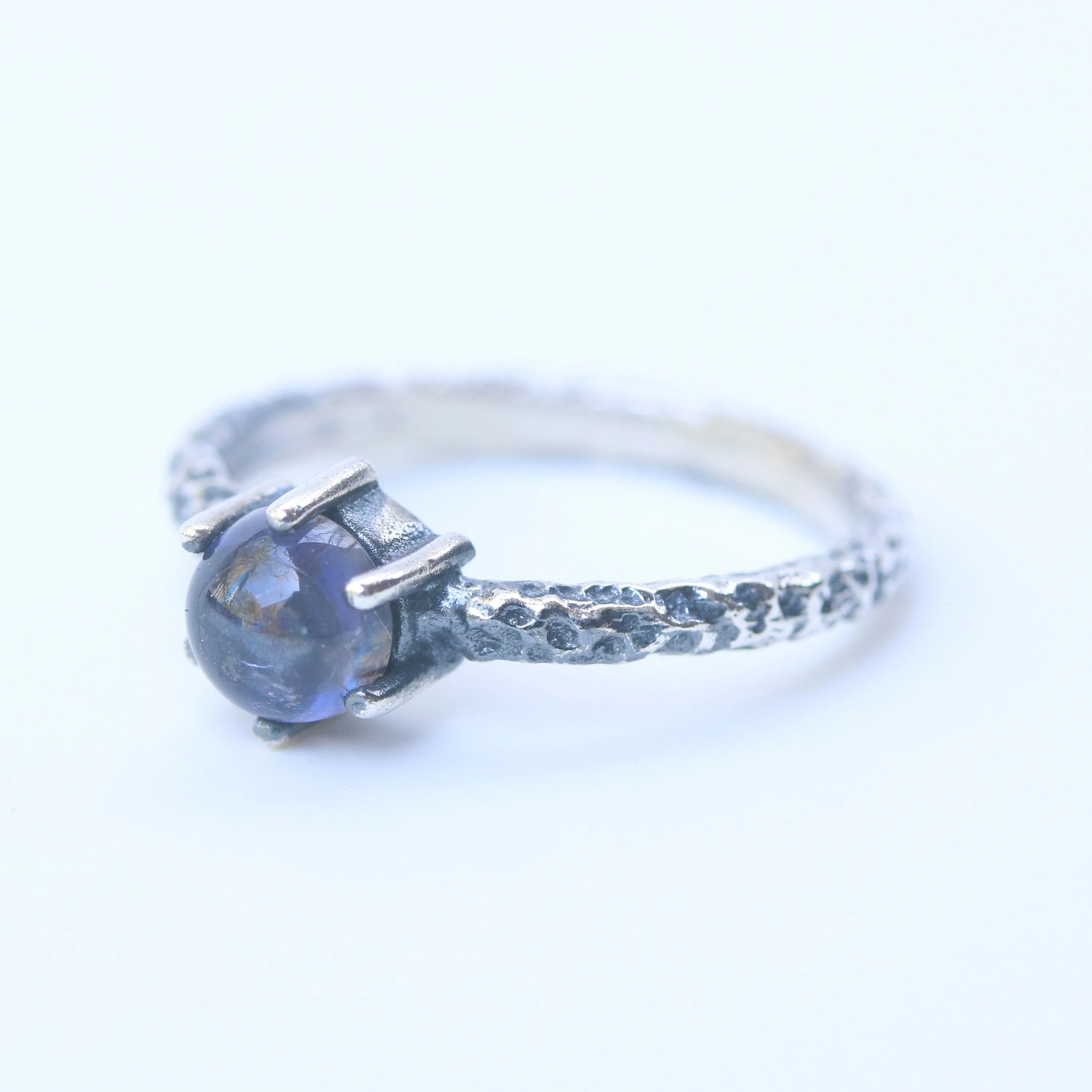 Round cabochon iolite ring in silver bezel and prongs setting with sterling silver oxidized hard texture band