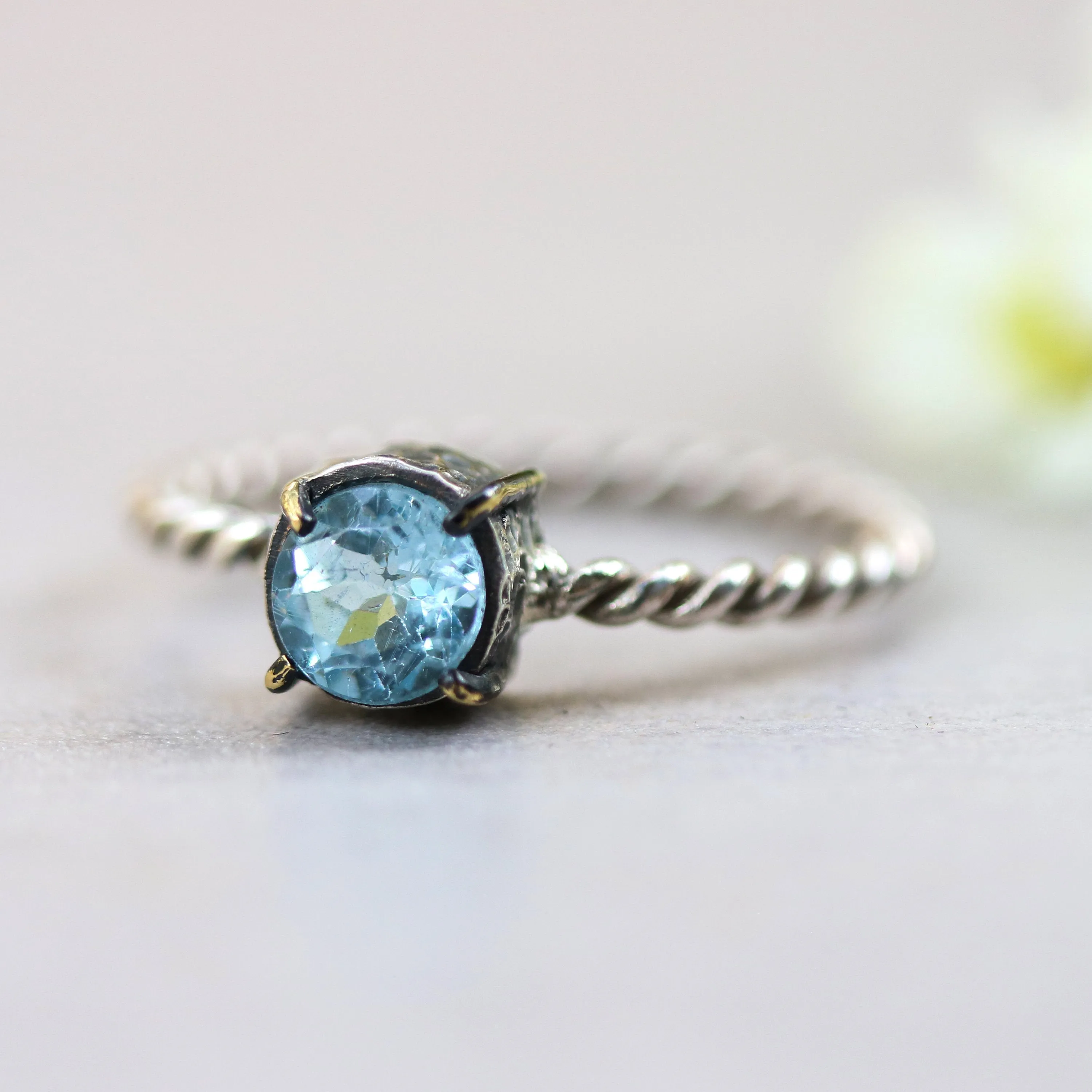 Round faceted blue topaz ring in silver bezel and brass prongs setting with sterling silver twist design band