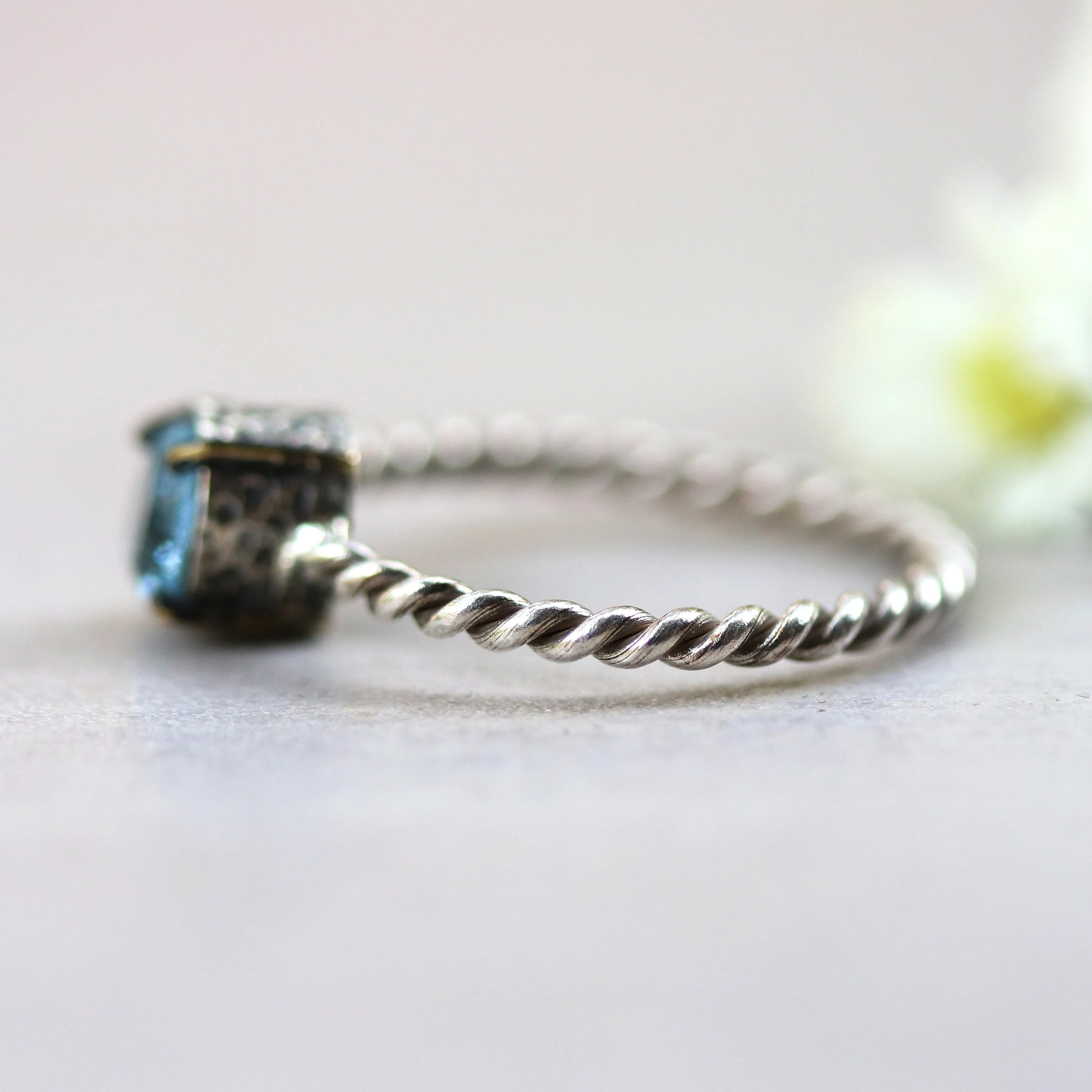Round faceted blue topaz ring in silver bezel and brass prongs setting with sterling silver twist design band