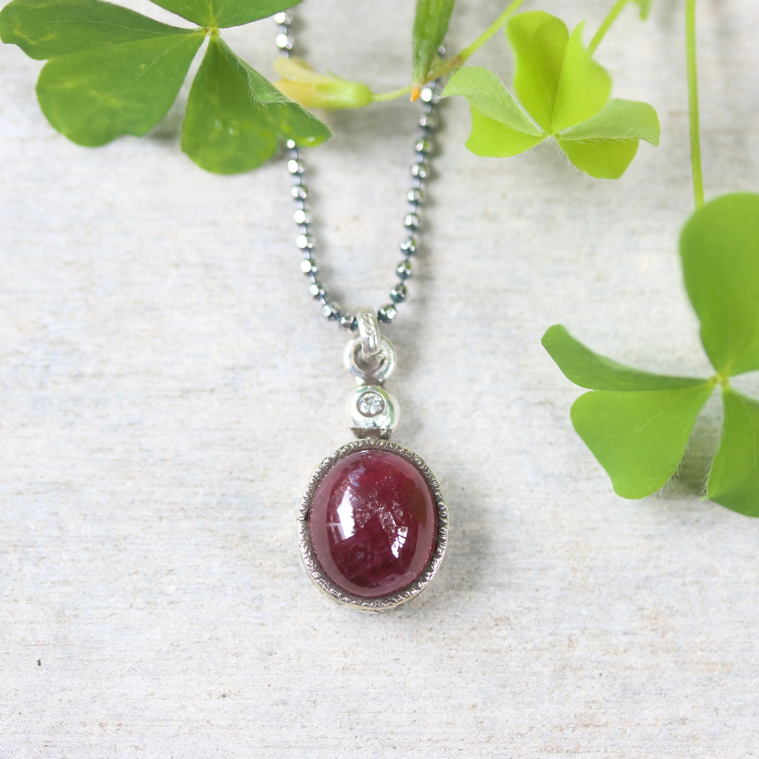 Ruby gemstone pendant necklace in silver bezel setting with tiny diamond on the top and oxidized sterling silver ball style chain