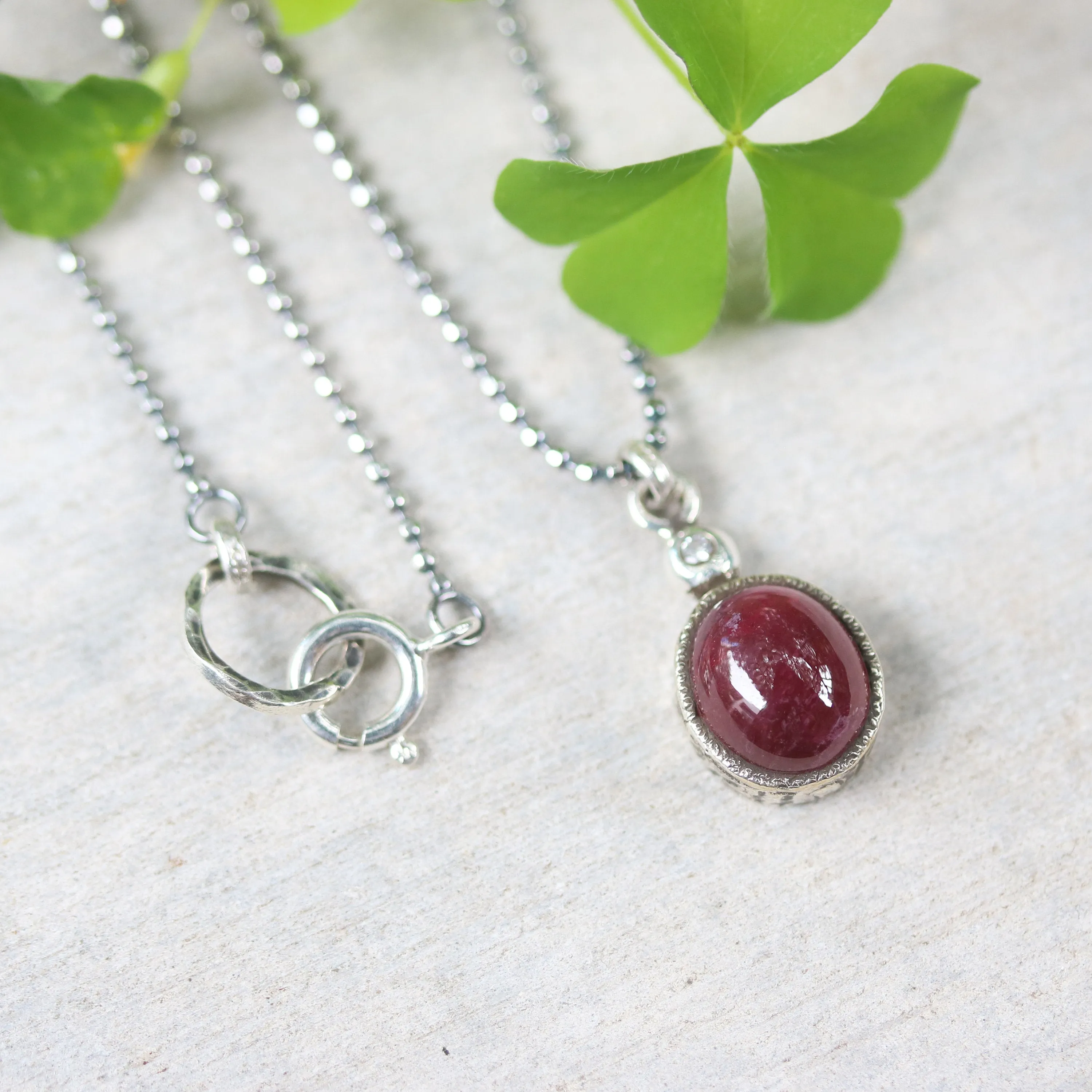 Ruby gemstone pendant necklace in silver bezel setting with tiny diamond on the top and oxidized sterling silver ball style chain