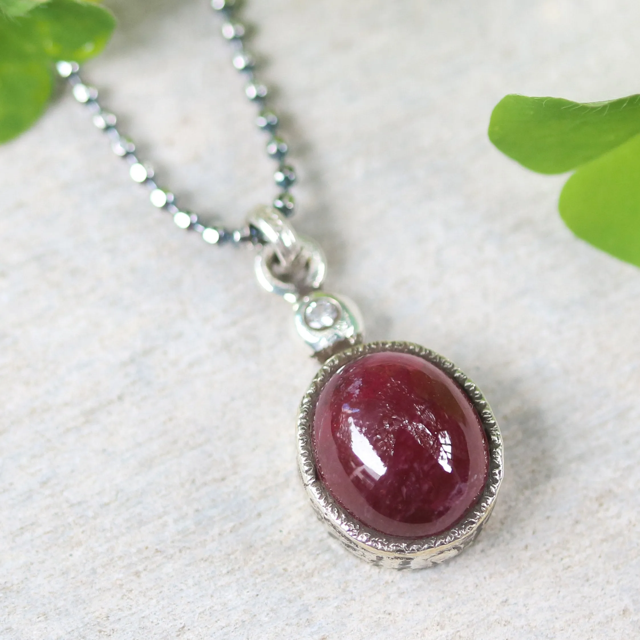 Ruby gemstone pendant necklace in silver bezel setting with tiny diamond on the top and oxidized sterling silver ball style chain